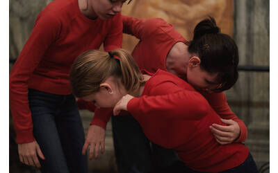 Tre danzatrici adolescenti danzano insieme, quasi abbracciate, in un museo. 